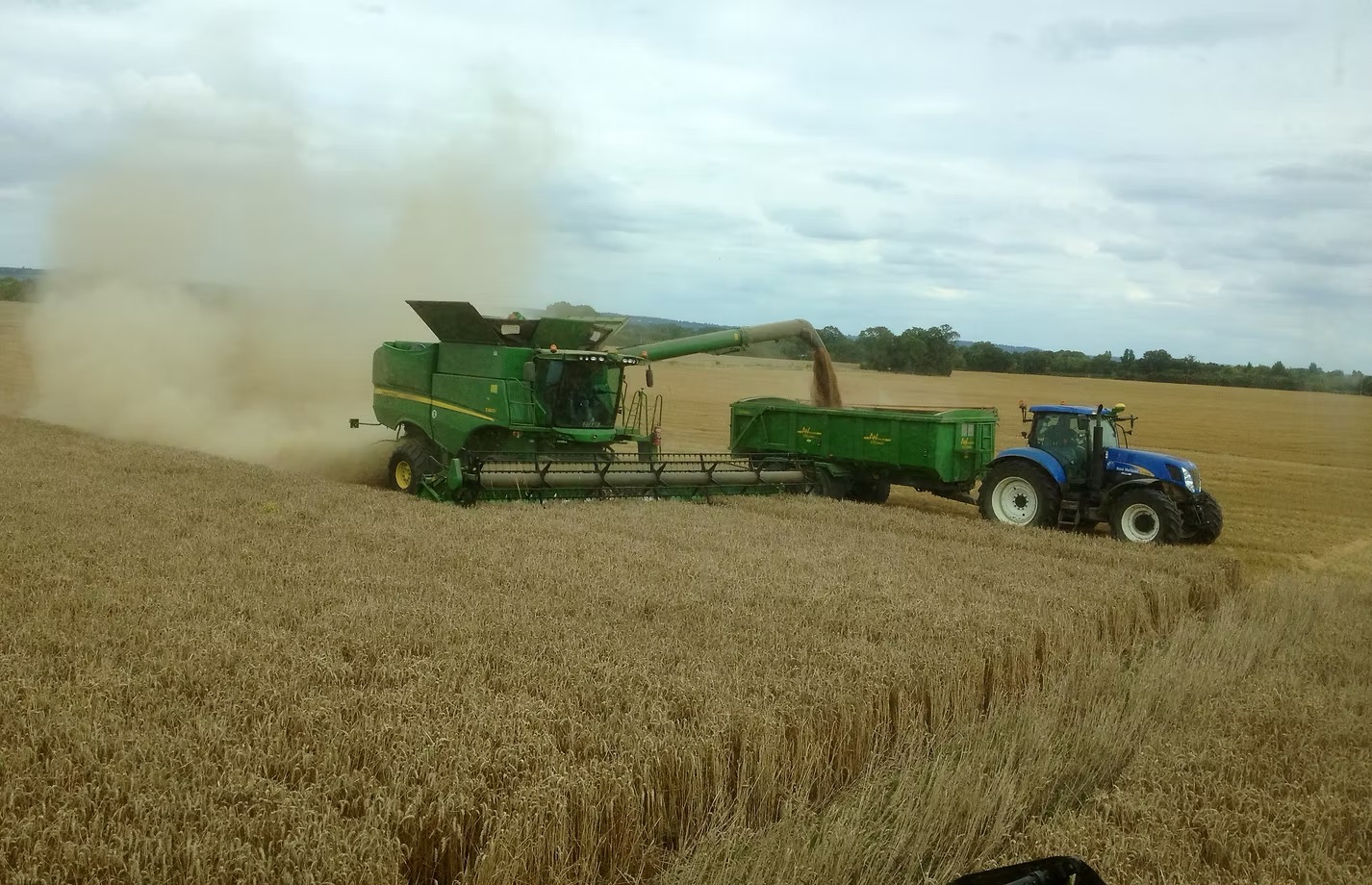 John Deere combine unloading grain into a trailer during harvest