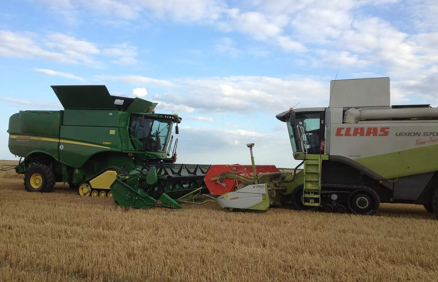 John Deere and CLAAS Lexion combines side by side in stubble